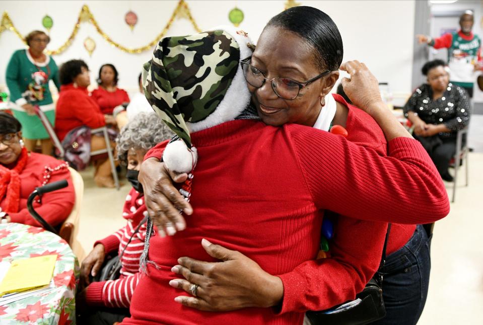Lola Lawson get a hug during the Martin Luther King, Jr. Neighborhood Association Christmas luncheon, Thursday morning, December 21, 2023.