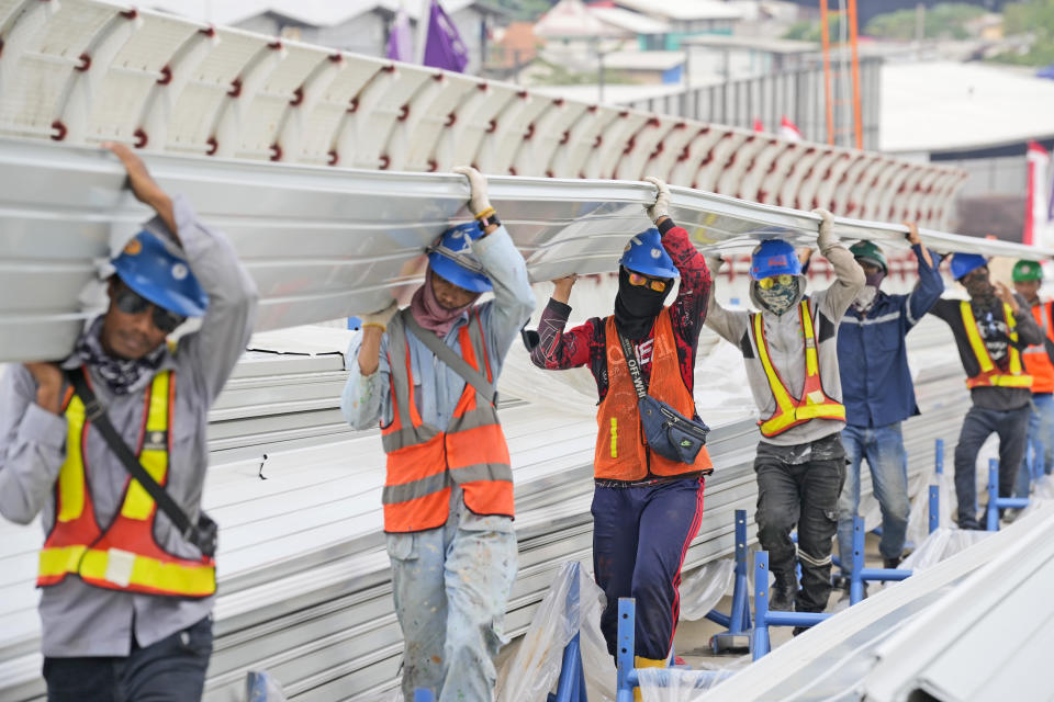 FILE - Workers carry a building material at the construction of Jakarta International Stadium in Jakarta, Indonesia, Tuesday, Oct. 26, 2021. Economies in the Asia-Pacific are forecast to slow sharply this year as decades-high inflation and the war in Ukraine compound geopolitical uncertainties and the aftereffects of the pandemic. (AP Photo/Dita Alangkara, File)