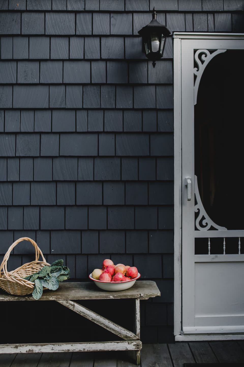 a basket with garden kale and apples on bench