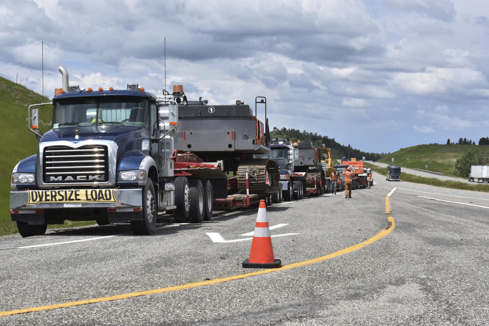 Local authorities are on the scene as heavy equipment is staged to begin removing the wreckage after a bridge collapse near Columbus, Mont., on Saturday, June 24, 2023. The bridge collapsed overnight, causing a train that was traveling over it to plunge into the water below. Authorities on Sunday were testing the water quality along a stretch of the Yellowstone River where mangled cars carrying hazardous materials remained after crashing into the waterway. (AP Photo/Matthew Brown)