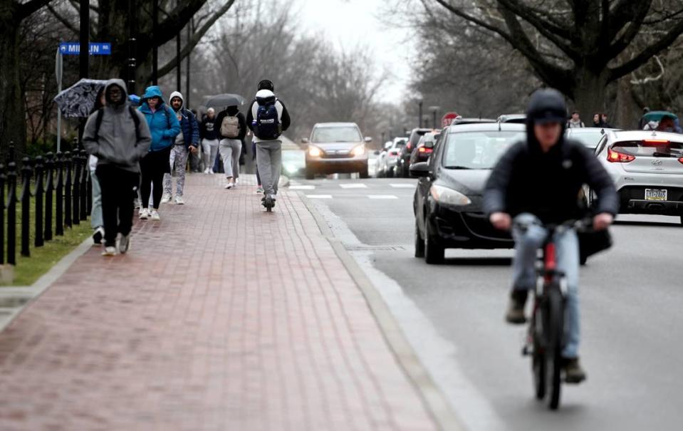 People walk, ride scooters, ride bikes and drive along Pollock Road on the Penn State campus on Friday, March 31, 2023.