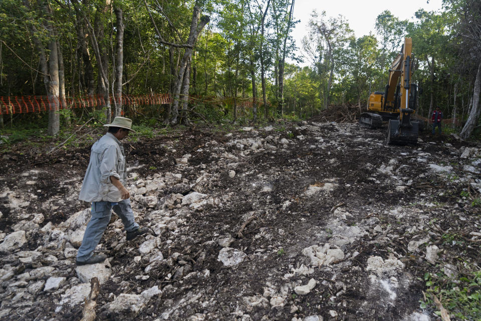 ARCHIVO - El activista ambiental Guillermo D. Christy camina hacia una excavadora inactiva estacionada en un camino a través del bosque que se está despejando para el Tren Maya en Akumal, estado de Quintana Roo, México, el 2 de agosto de 2022. Este tramo de la ruta del tren es controvertido porque corta una franja de más de 68 millas (110 kilómetros) a través de la jungla sobre algunos de los sistemas de cuevas subterráneas más complejos y frágiles del mundo, entre los centros turísticos de Cancún y Tulum. (Foto AP/Eduardo Verdugo, Archivo)