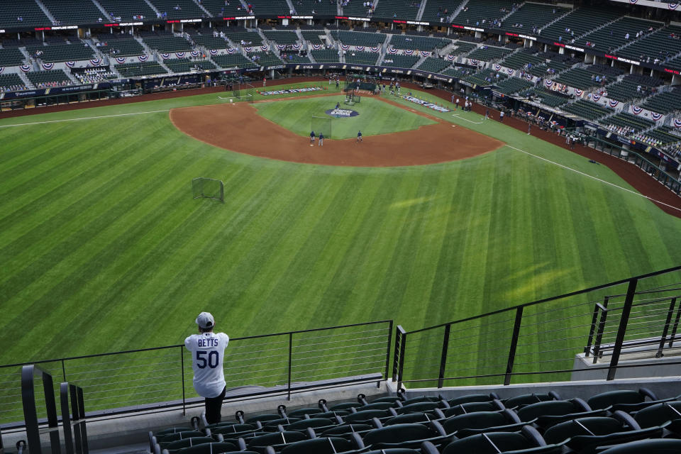 A fan watches batting practice from center field before Game 1 of the baseball World Series between the Los Angeles Dodgers and the Tampa Bay Rays Tuesday, Oct. 20, 2020, in Arlington, Texas.(AP Photo/Sue Ogrocki)