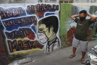 A man wears a face mask to help curb the spread of the new coronavirus near a coronavirus awareness mural at Rawa Pasung village in Bekasi on the outskirts of Jakarta, Indonesia, Thursday, July 23, 2020. (AP Photo/Achmad Ibrahim)