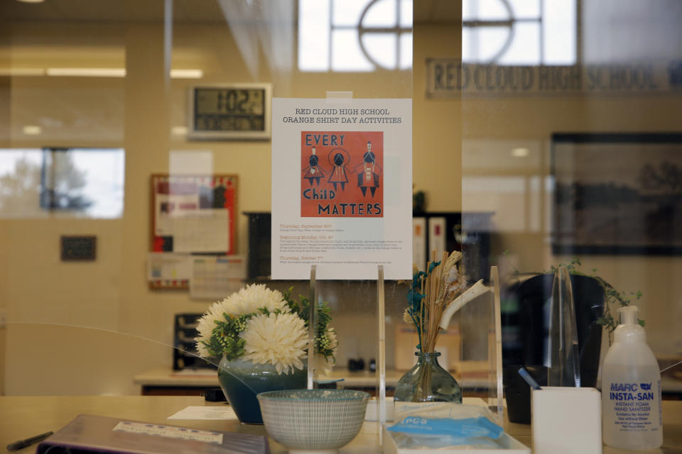 A flyer for Orange Shirt Day is posted on the reception desk of Red Cloud Indian School on Sept. 30, 2021, in Pine Ridge, S.D. Students and teachers wore orange in solidarity with Indigenous children of past generations who suffered cultural loss, family separation and sometimes abuse and neglect while compelled to attend hundreds of residential schools that once dotted the map across the United States and Canada from the late 19th to the mid-20th centuries. (AP Photo/Emily Leshner)