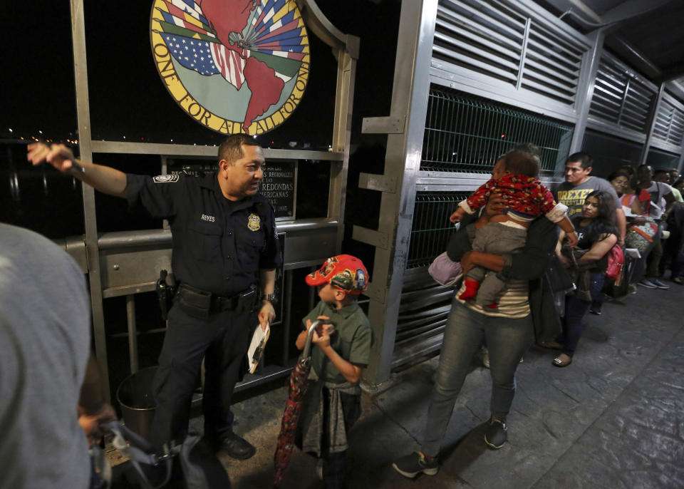 FILE - In this Sept. 17, 2019, file photo, a U.S. Customs and Border Protection officer gives instructions to migrants who are on their way to apply for asylum in the United States, on International Bridge 1 as they depart Nuevo Laredo, Mexico. The Trump administration on Wednesday, July 8, 2020, proposed empowering border authorities to deny asylum to people from countries with widespread, deadly communicable disease, its latest in a string of regulations before the November elections to dramatically raise the bar on who qualifies for humanitarian protections. (AP Photo/Fernando Llano, File)