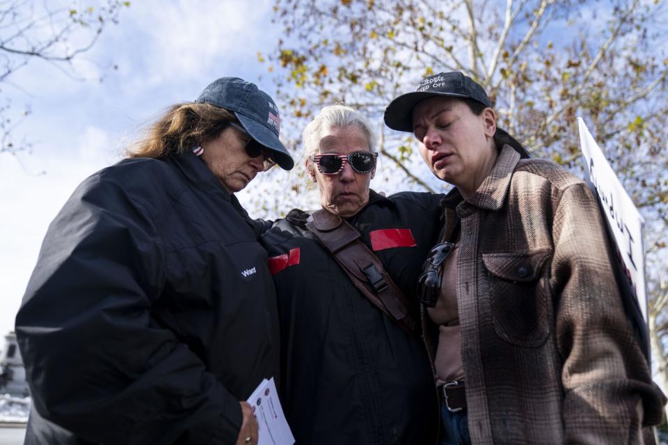 Three people stand and pray outside