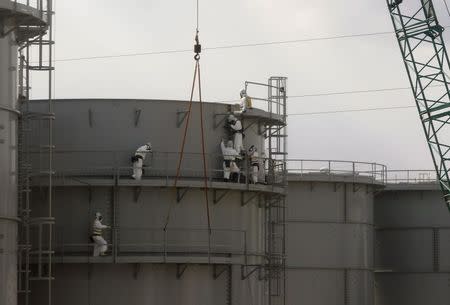 Workers wearing protective suits and masks constructing water tanks is seen through a bus window at Tokyo Electric Power Co. (TEPCO)'s tsunami-crippled Fukushima Daiichi nuclear power plant in Fukushima prefecture in this February 20, 2012 file photo. REUTERS/Issei Kato