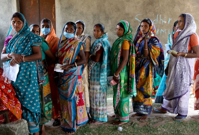 Women wait in line to cast their vote at a polling station in Purulia