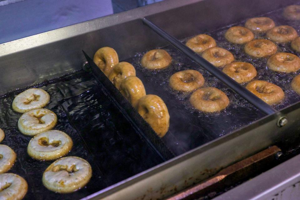 Doughnuts are fried in sunflower oil at the Franklin Cider Mill on Saturday, Oct. 30, 2021. Kevin Michaels, head of doughnut production, says the process takes about two minutes from the doughnut mix being poured to them being cooked and sent down the line.