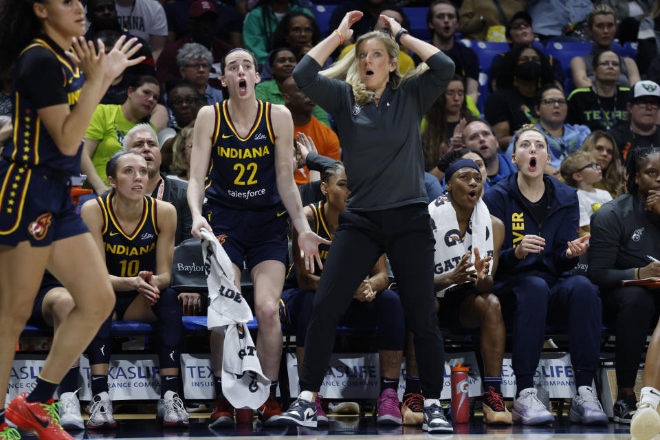 CORRECTS FROM CAITLYN TO CAITLIN - Indiana Fever guard Caitlin Clark (22) and head coach Christine Sides, center right, react after a play during the second half of an WNBA basketball game against the Dallas Wings in Arlington, Texas, Friday, May 3, 2024. (AP Photo/Michael Ainsworth)