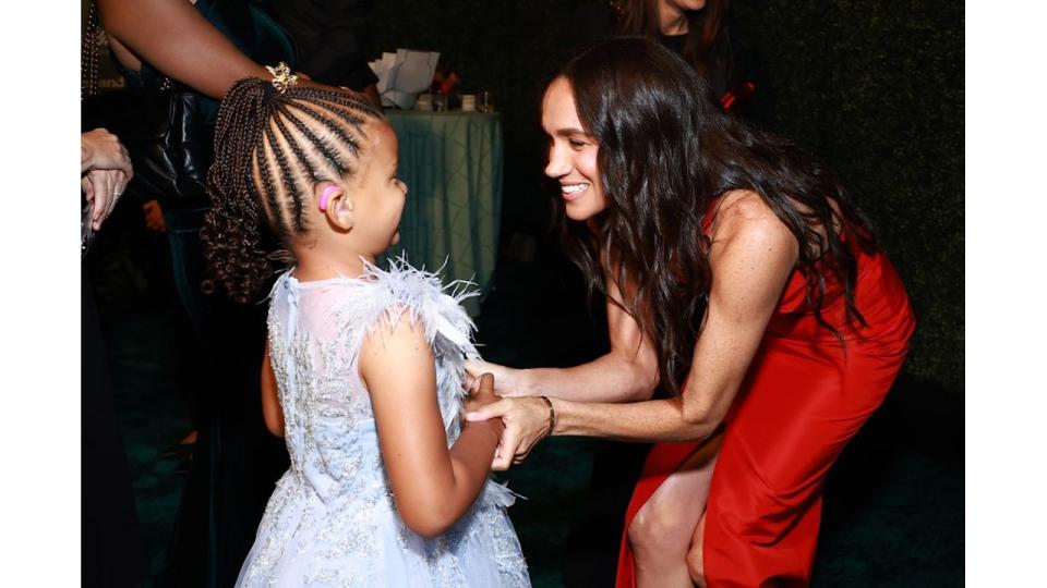 woman speaking to young girl at gala