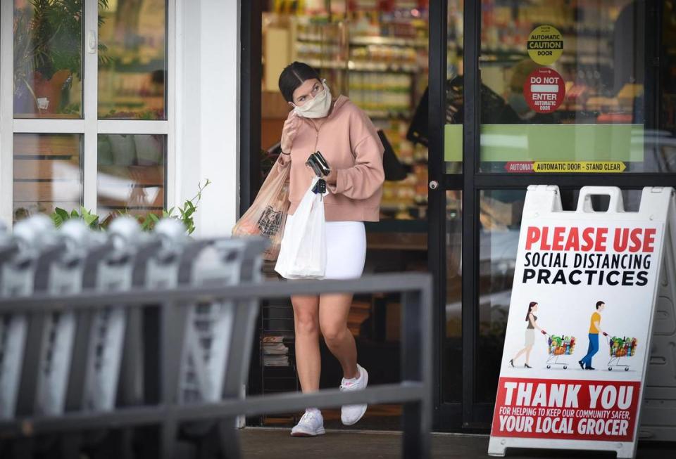 Kaleigh Smith of Prairie Village reaches to remove her mask after shopping Monday at the Hen House Market in the Prairie Village Shopping Center. Smith said she has not yet been vaccinated against the coronavirus.