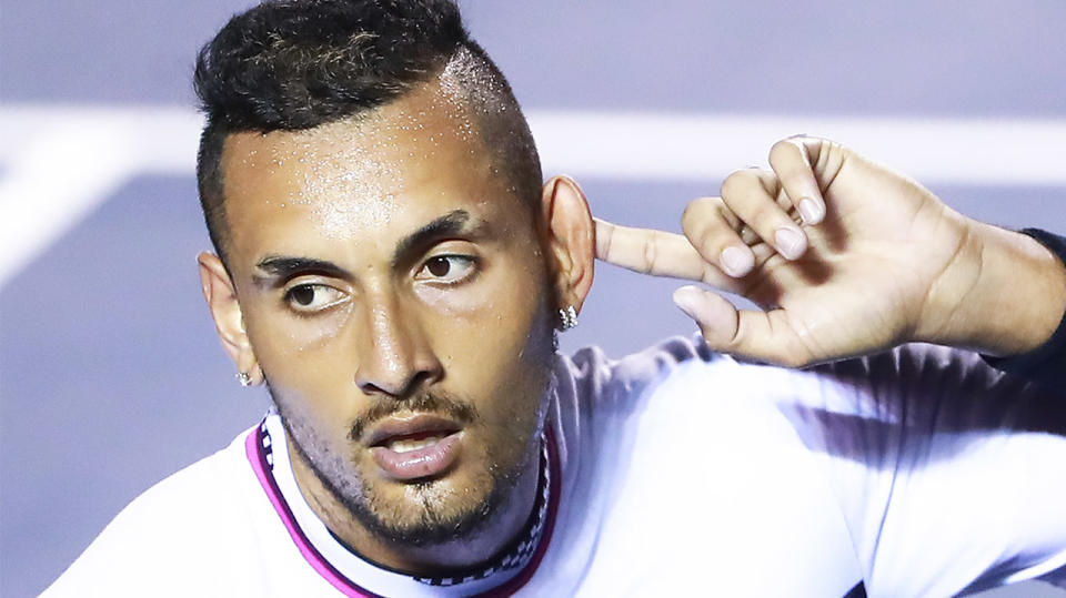 Nick Kyrgios pointing to his ear and celebrating after defeating Rafael Nadal.