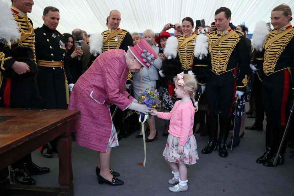The Queen receives a posy from a child during a reception following the Hyde Park parade. (AFP/Getty Images)