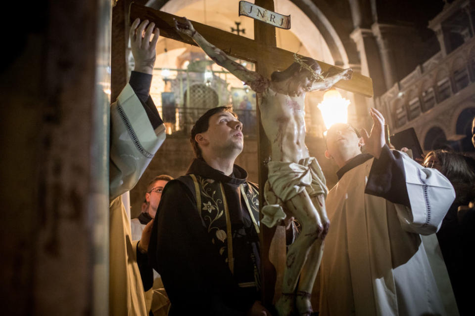 Dos sacerdotes con un Cristo crucificado.