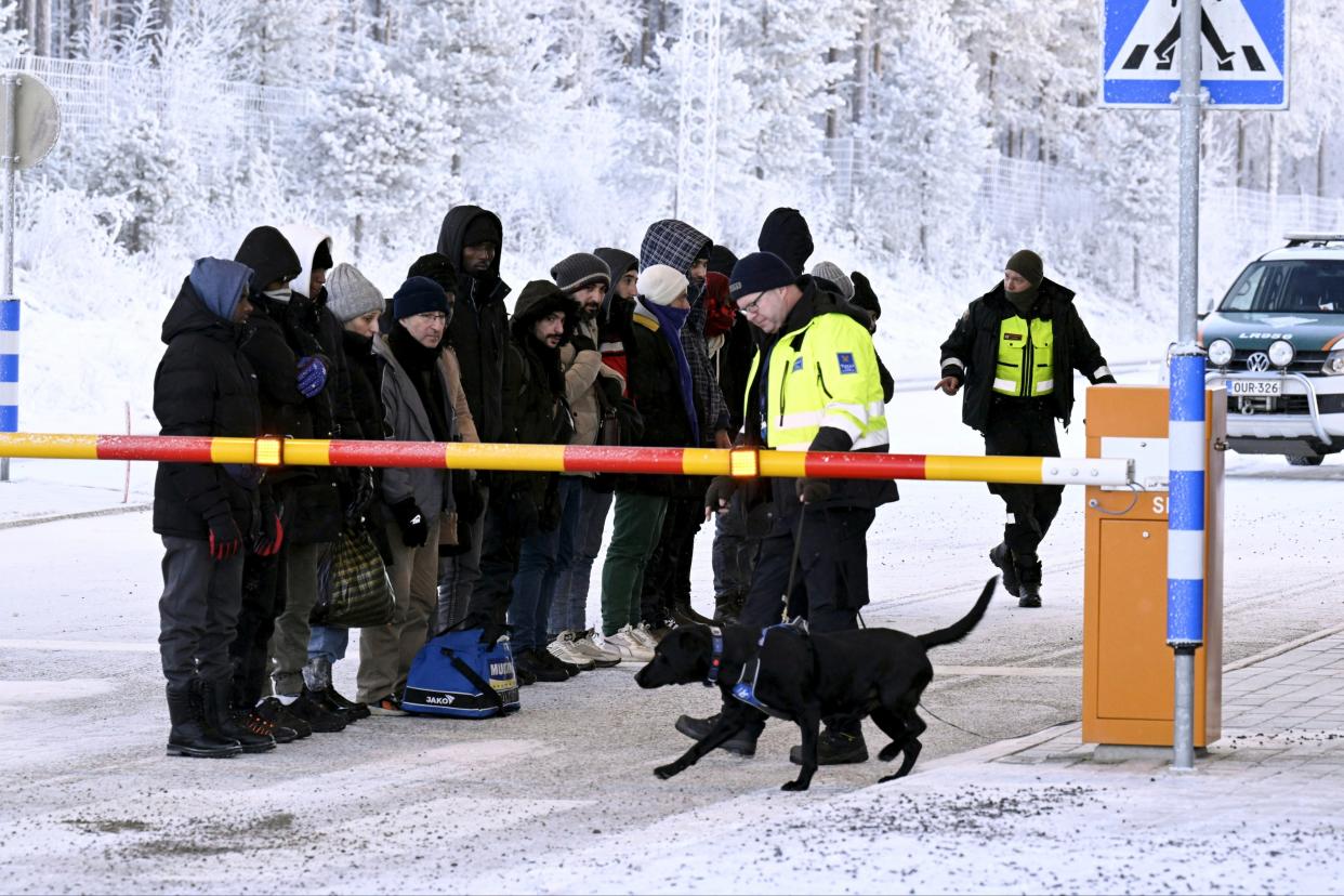 Migrants look at a Finnish Customs official’s dog at the international border crossing with Russia earlier this week (AP)