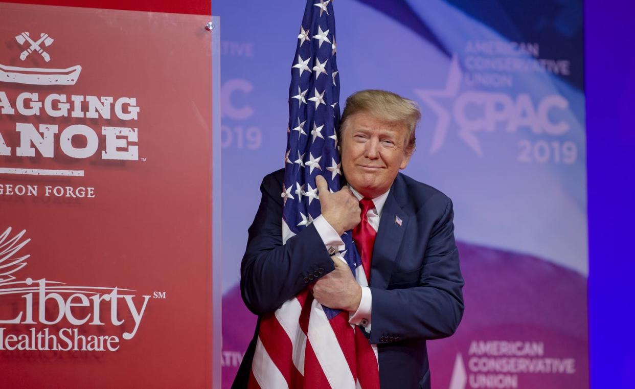 <span class="caption">Trump hugs the American flag at a 2019 convention of political conservatives. </span> <span class="attribution"><a class="link " href="https://www.gettyimages.com/detail/news-photo/president-donald-trump-hugs-the-u-s-flag-during-cpac-2019-news-photo/1133214208?adppopup=true" rel="nofollow noopener" target="_blank" data-ylk="slk:Tasos Katopodis/Getty Images;elm:context_link;itc:0;sec:content-canvas">Tasos Katopodis/Getty Images</a></span>