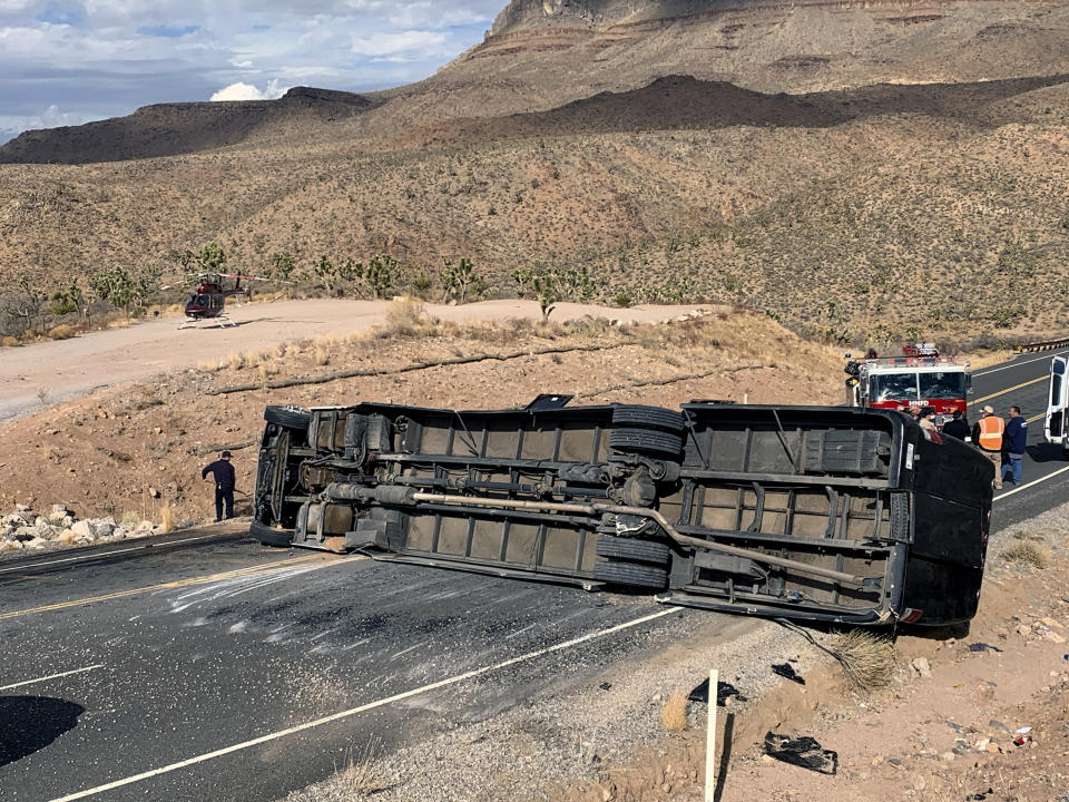 This photo provided by the Mohave County Sheriff's Office shows a Las Vegas-based tour bus that crashed, Jan. 22, 2021, in Dolan Springs, Ariz. A crash report on the tour bus that flipped on the way to the west end of the Grand Canyon, killing one passenger, doesn't draw any conclusion about the cause but points to speed as a factor. Four dozen people from across the country were on the bus operated by Comedy On Deck Tours when it veered into a dirt embankment, over ruts and rocks, and hit Joshua trees Jan. 22. (Mohave County Sheriff's Office via AP)