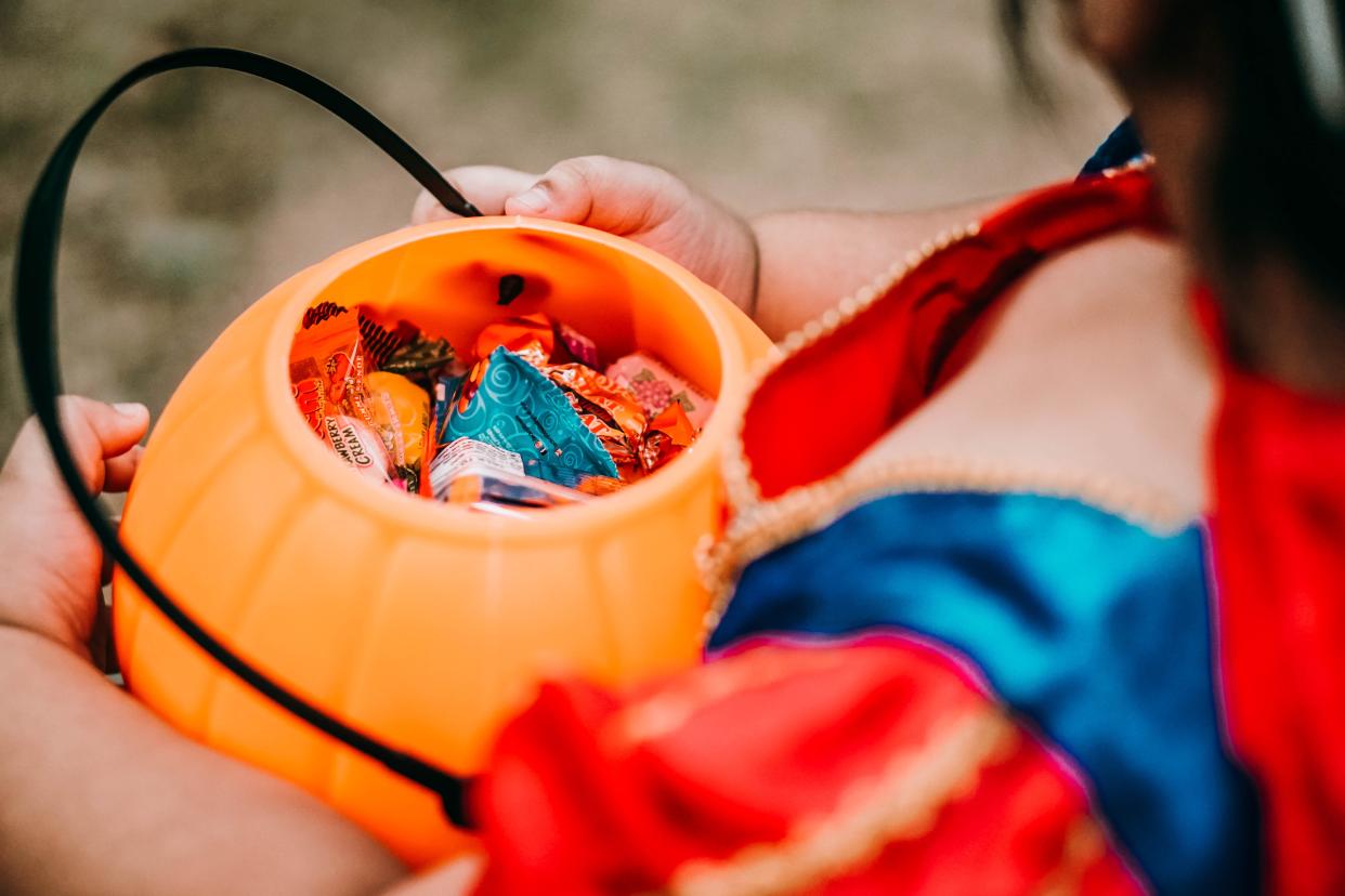 Baby girl holding candies in pumpkin basket