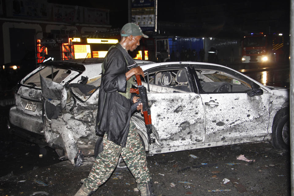 A Somalia soldier walks past destroyed cars after one of two car bombs, in Mogadishu, Somalia, Sunday Aug. 5, 2018. Two car bombs hit Somalia on Sunday, killing at least six people. Somalia's Islamic extremist rebels claimed responsibility for the first suicide car bomb blast that that killed four people when it exploded near the gate of a military base in Afgoye town, 30 kilometers (18 miles) northwest of Mogadishu. (AP Photo/Farah Abdi Warsameh)