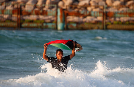 A demonstrator holds a Palestinian flag during a protest calling for lifting the Israeli blockade on Gaza, at the sea near the maritime border with Israel, in the northern Gaza Strip September 17, 2018. REUTERS/Mohammed Salem