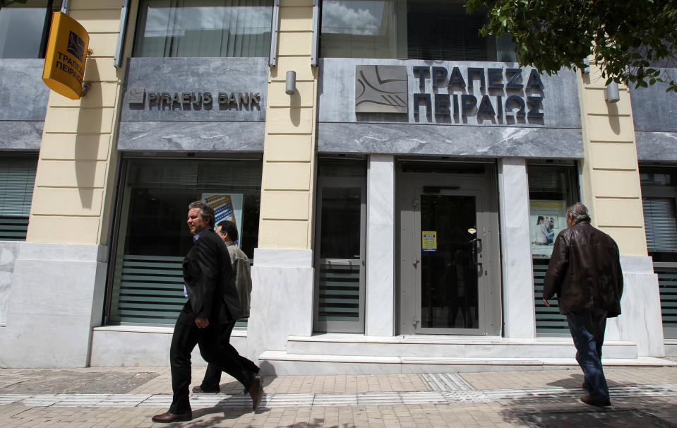 Pedestrians pass outside a Piraeus Bank branch in Athens, Friday, April 20, 2012. Greek banks will publish their annual reports later Friday, which are expected to include severe losses resulting from their participation in the country's massive private debt writedown earlier this year. (AP Photo/Thanassis Stavrakis)