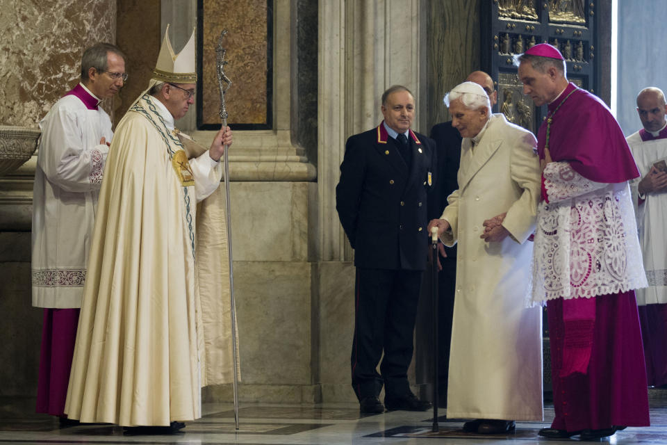 FILE - Pope Francis watches Pope Emeritus Benedict XVI enter St. Peter's Basilica accompanied by Monsignor Georg Gaenswein, right, at the Vatican, on Dec. 8, 2015. Pope Benedict XVI’s 2013 resignation sparked calls for rules and regulations for future retired popes to avoid the kind of confusion that ensued. Benedict, the German theologian who will be remembered as the first pope in 600 years to resign, has died, the Vatican announced Saturday Dec. 31, 2022. He was 95. (AP Photo/Andrew Medichini, File)