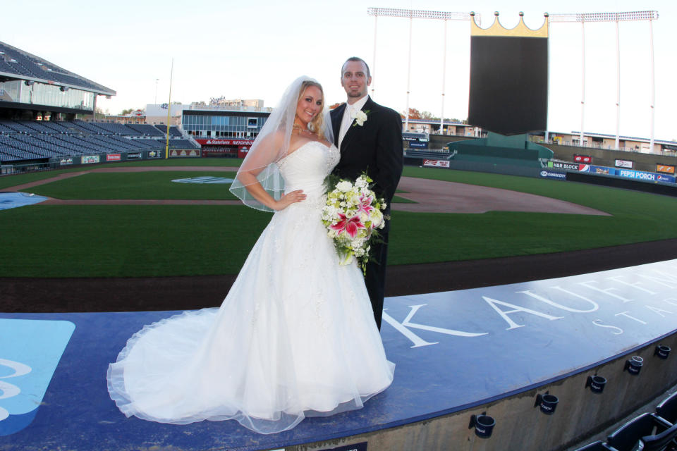 This Oct. 20, 2012 photo released by Ashley Crank shows her posing with her husband Cody Crank during their wedding at Kauffman Field in Kansas City. Some couples, find that the massive stadiums where they enjoy hearing the crack of the bat can also be the perfect place to hear their beloved say, "I do." (AP Photo/Jessica Thomas)