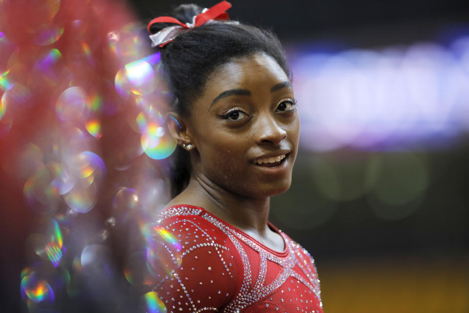 FILE - In this Nov. 2, 2018, file photo, Simone Biles talks to other gymnasts as she warms up on the second and last day of the apparatus finals of the Gymnastics World Championships at the Aspire Dome in Doha, Qatar. With the Olympics a year away, the world's best gymnast believes there's always a new wrinkle, twist or turn to be added to her routine to stay ahead of her competitors. Biles will face some of American challengers in this weekend's GK US Classic, a prelude to next month's Nationals.  (AP Photo/Vadim Ghirda, FIle)