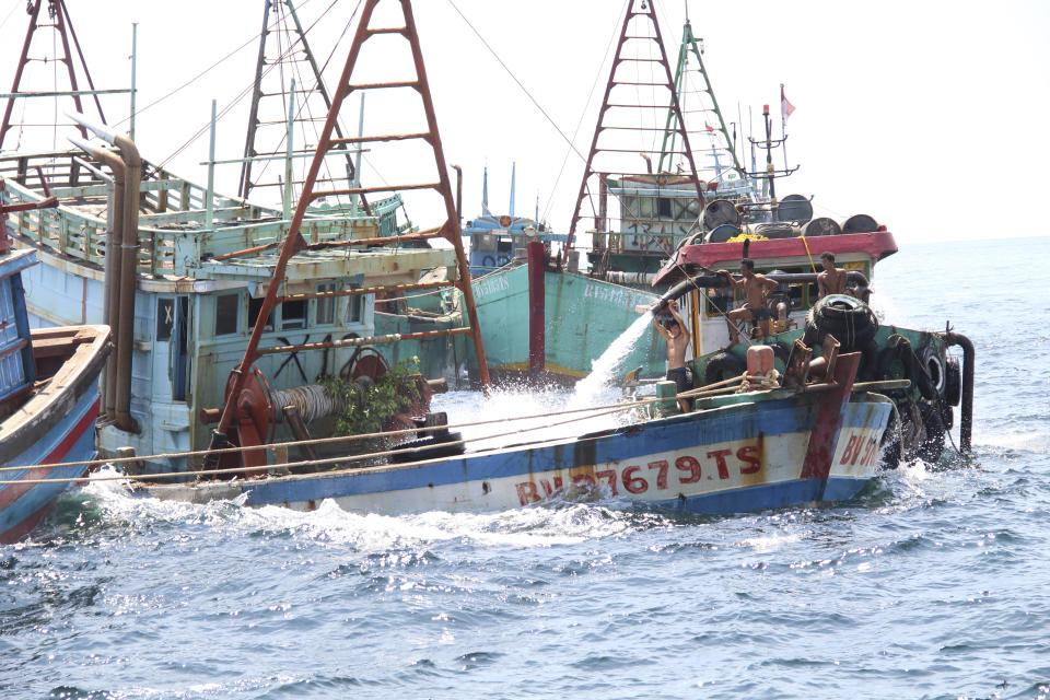 Workers flood the cargo bay of a Vietnamese-flagged boats with water to sink it in the waters off Datuk Island, West Kalimantan, Indonesia, Saturday, May 4, 2019. Authorities sank 51 foreign fishing boats caught operating illegally in the Indonesian waters as it resumed its tough stance against poaching in the country. (AP Photos/William Pasaribu)