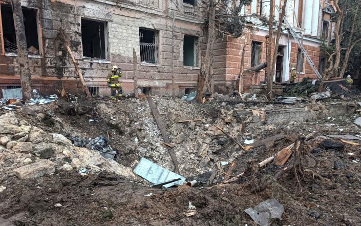 A rescuer stands next to a crater left by a Russian missile strike in Mykolaiv - STRINGER/REUTERS