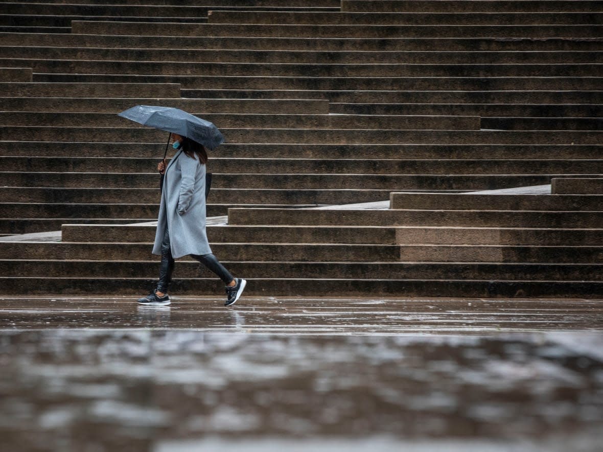 A woman is seen walking through the rain in Vancouver. (Ben Nelms/CBC - image credit)