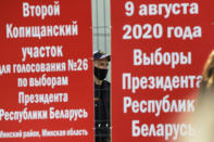 A police officer stands behind a fence of a polling station during the Belarusian presidential election in Minsk, Belarus, Sunday, Aug. 9, 2020. Banners read at left: "Second Kopyshansky polling station N26 for the election of President of the Republic of Belarus, Minsk's district of Minsk region", and at right, "9 of August 2020 year. The election of President of the Republic of Belarus". Belarusians are voting on whether to grant incumbent president Alexander Lukashenko a sixth term in office, extending his 26-years rule, following a campaign marked by unusually strong demonstrations by opposition supporters. (AP Photo/Sergei Grits)
