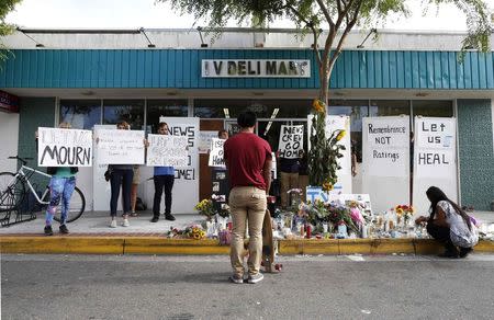 People protest the presence of news crews as a man stands in front of a makeshift shrine for 20-year-old UCSB student Christopher Michael-Martinez outside a deli that was one of nine crime scenes after series of drive-by shootings that left 7 people dead in the Isla Vista neighborhood of Santa Barbara, California May 26, 2014. REUTERS/Lucy Nicholson