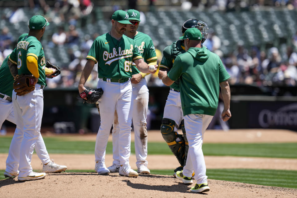 Oakland Athletics pitcher Hogan Harris, center front, hands the ball to manager Mark Kotsay, right, while being pulled during the sixth inning of a baseball game against the New York Yankees in Oakland, Calif., Thursday, June 29, 2023. (AP Photo/Godofredo A. Vásquez)