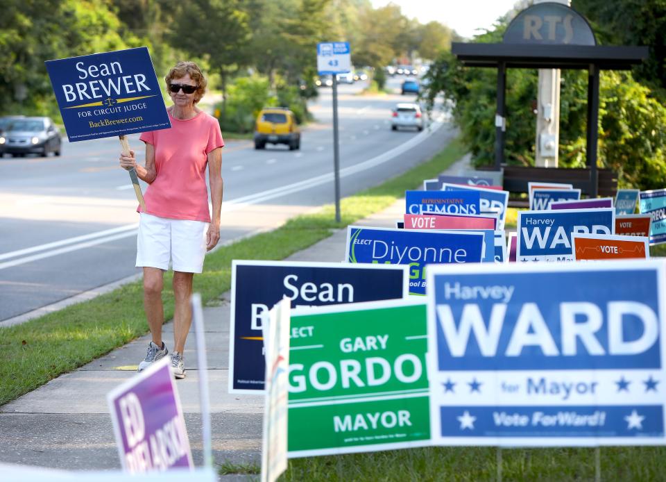 A supporter of Sean Brewer, a candidate for the circuit judge, walks along NW 43rd Street outside the Millhopper Branch of the Alachua County Library, in Gainesville FL. August 18, 2022.