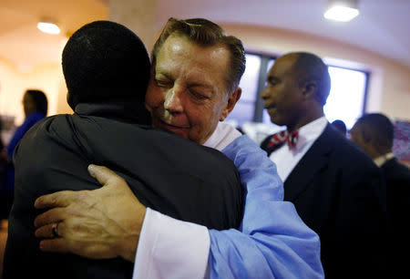 Father Michael Pfleger (C) hugs a parishioner after a Sunday Service at Saint Sabina Church in Chicago, Illinois, U.S., December 4, 2016. REUTERS/Jim Young