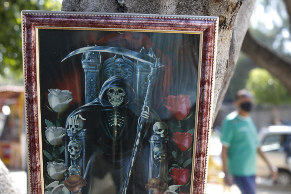 An image of Santa Muerte, or Sacred Death, hangs on a tree on a block where family members typically wait for news of their loved ones outside Balbuena General Hospital, which is treating both patients with COVID-19 and those with other conditions, in Mexico City, Monday, May 25, 2020. Authorities have predicted that coronavirus cases in the city would peak in May, with reopening measures currently slated for mid-June. (AP Photo/Rebecca Blackwell)