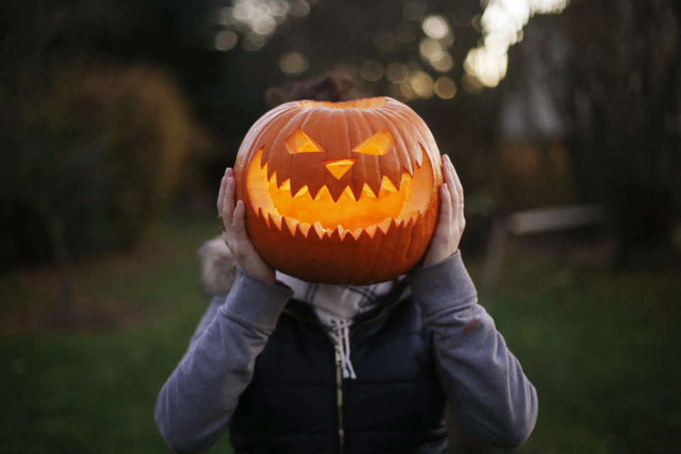 A girl with Halloween pumpkin in front of her head