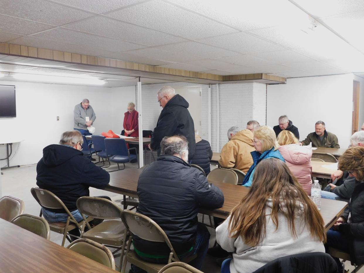 Craig Johnstone of Grinnell prays before the caucus meeting is called to order on Monday at the Heartland Co-op in Malcom.