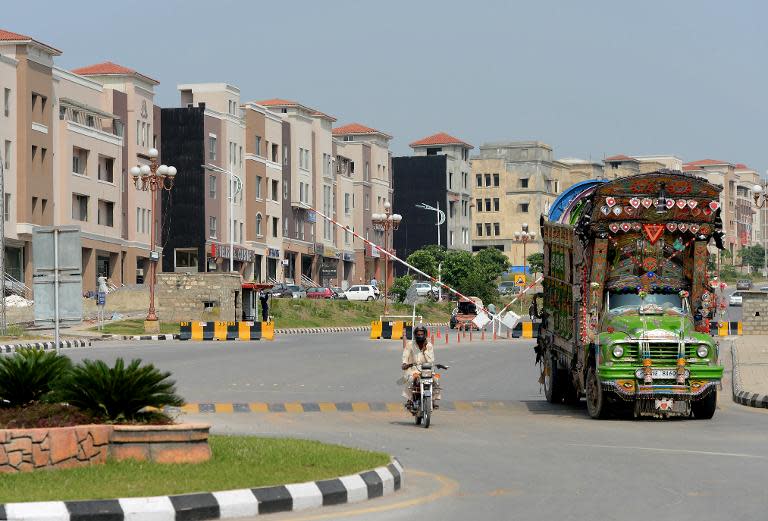 Pakistani motorists drive past under-construction buildings at the Bahria Town private development in Rawalpindi on October 2, 2013