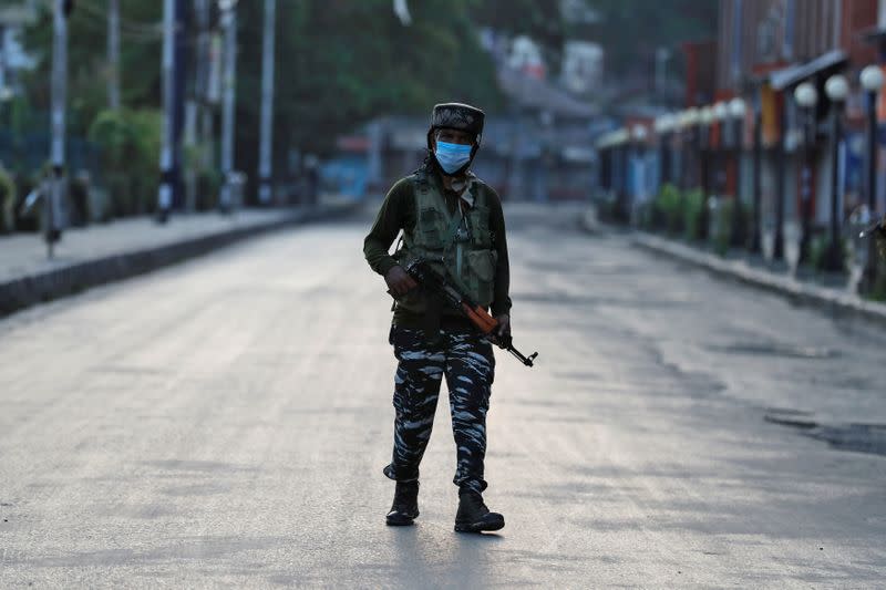 An Indian Central Reserve Police Force officer patrols on an empty street during a lockdown on the first anniversary of the revocation of Kashmir's autonomy in Srinagar