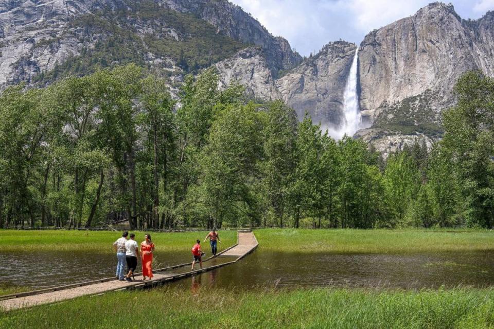 Yosemite National Park visitors contemplate crossing a flooded meadow boardwalk across from Upper Yosemite Falls in Yosemite Valley on Tuesday, June 13, 2023.