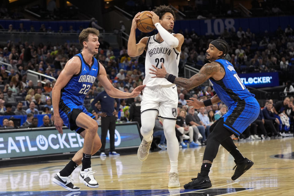 Brooklyn Nets forward Jalen Wilson (22) looks to pass the ball as he gets caught between Orlando Magic forward Franz Wagner (22) and center Wendell Carter Jr., right, during the second half of an NBA basketball game, Tuesday, Feb. 27, 2024, in Orlando, Fla. (AP Photo/John Raoux)