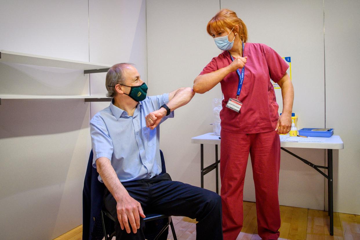 Irish Prime Minister Micheal Martin (L) bumps elbows with Brenda Dillon, assistant director of nursing at Health Service Executive (HSE), after receiving his first dose of the AstraZeneca/Oxford vaccine against coronavirus at the vaccination center at City Hall in Cork on May 9, 2021.