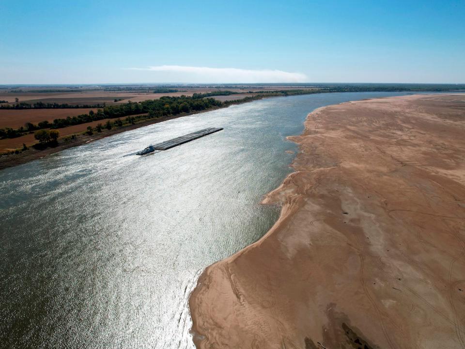 aerial view of barge traveling down thin mississippi river with vast dry banks