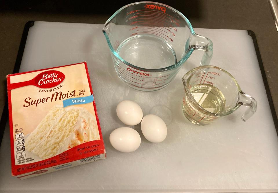 A Betty Crocker boxed cake mix on a white tray with measuring cups with oil and water and eggs
