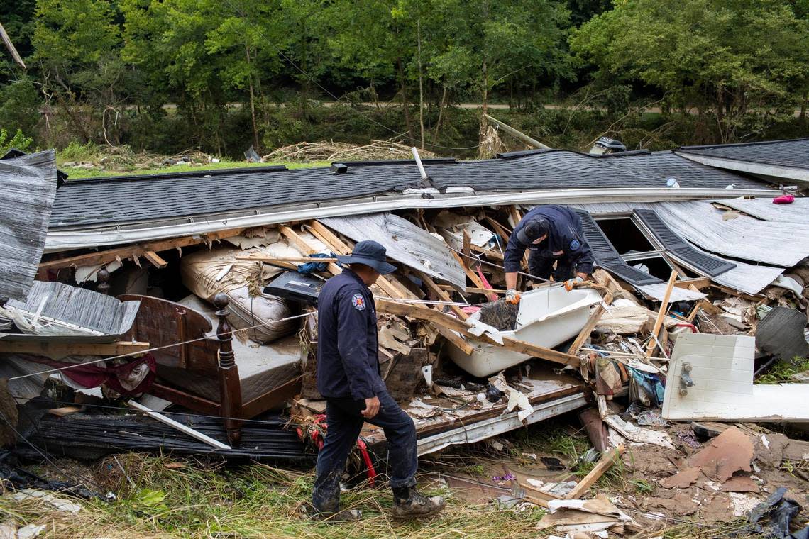 Members of the Lexington Fire Department look through the wreckage of a home while operating as search and rescue units along KY-476 along Troublesome Creek in Breathitt County, Ky., Sunday, July 31, 2022.