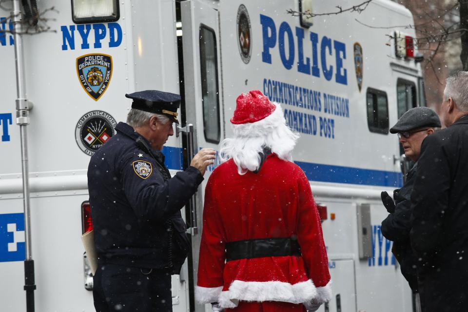 An NYPD police officer speaks with a reveller dressed as Santa Claus during the SantaCon event in New York December 14, 2013. Every year since 1997, thousands of men and women have dressed up as Santas, elves, reindeer or some other holiday confection and descended on the city's streets for a daylong bar crawl that begins with good cheer and, for many, inevitably ends in a blurry booze-soaked haze. Many come from Long Island and New Jersey, getting a head start on the festivities on the train ride into the city. REUTERS/Eduardo Munoz (UNITED STATES - Tags: SOCIETY ENTERTAINMENT)